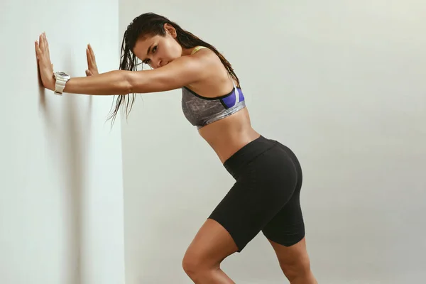 Mujer deportiva en ropa deportiva de moda y reloj de fitness cerca de la pared — Foto de Stock