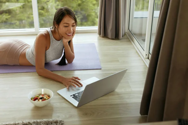 Menina sorrindo usando computador sentado no chão em casa de manhã — Fotografia de Stock