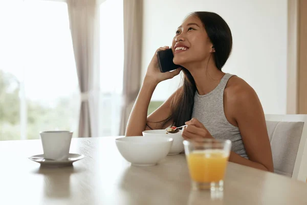 Woman using mobile phone while having breakfast at home — Stock Photo, Image