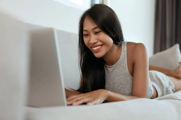 Mulher com computador portátil no sofá na sala de estar em casa — Fotografia de Stock