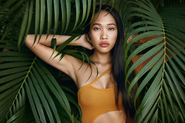 Belleza. Modelo de mujer con pelo largo y hojas de palmera —  Fotos de Stock