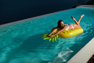 Havuz partisi. Yüzme havuzunda ananas yüzen eğlenen kadın