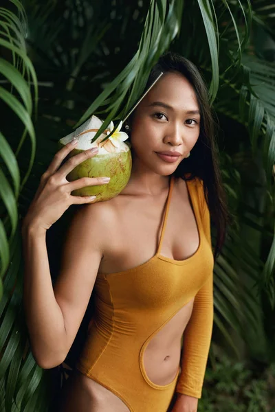 Moda. Mujer en traje de baño con coco verde en la naturaleza tropical — Foto de Stock