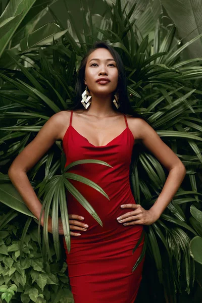 Fashion. Woman model in red dress with green palm leaves — Stock Photo, Image