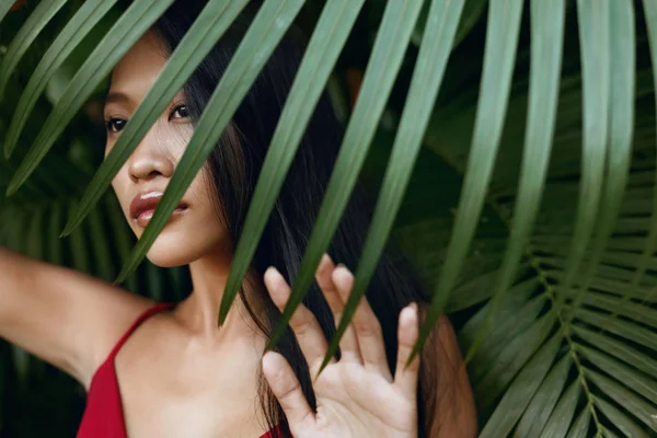 Beleza. Mulher asiática bonita com folha de palma sobre rosto na natureza — Fotografia de Stock