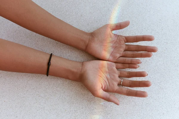 Arco iris en las manos. Mano femenina con pequeña luz de arco iris en las palmas — Foto de Stock