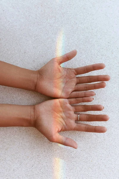 Arco iris en las manos. Mano femenina con pequeña luz de arco iris en las palmas — Foto de Stock