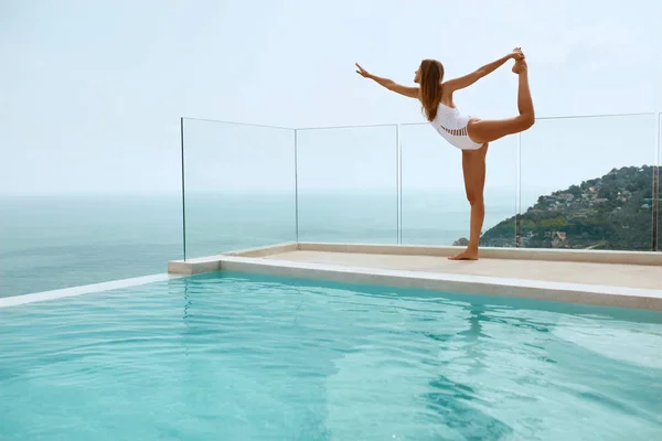 Yoga. Mulher de maiô esticando as pernas perto da piscina — Fotografia de Stock