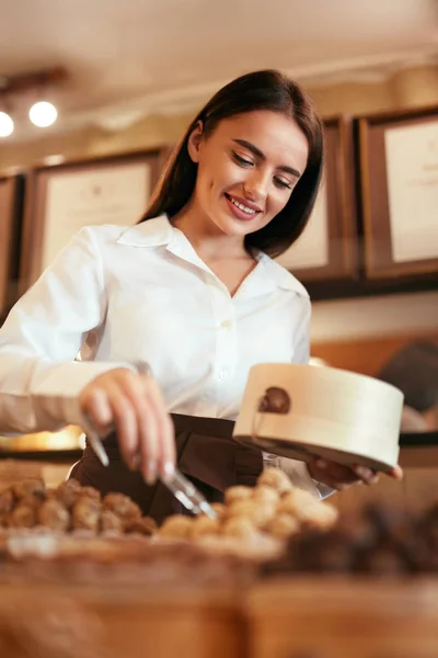 Confeitaria. Mulher vendendo doces de chocolate na loja — Fotografia de Stock