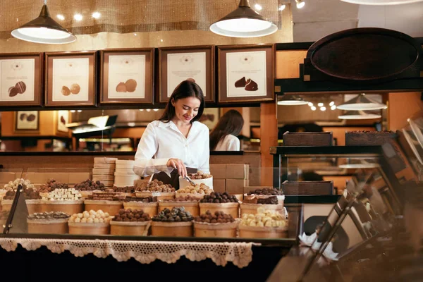 Konfektyr. Kvinna som säljer choklad godis i butik — Stockfoto