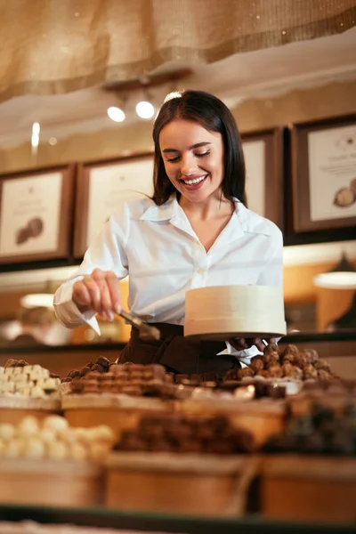 Confitería. Mujer vendiendo caramelos de chocolate en la tienda — Foto de Stock