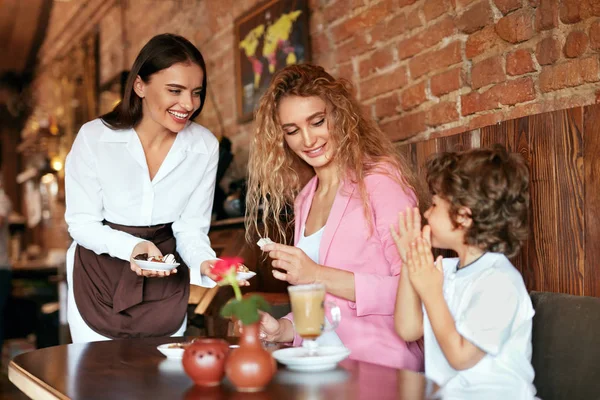 Familia en el Café. Camarera sirviendo chocolate a madre e hijo — Foto de Stock