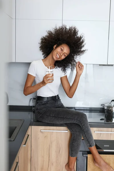 Drink water. Happy woman with glass of fresh water in kitchen