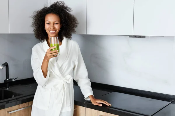 Femme buvant du jus de désintoxication vert, boisson smoothie dans la cuisine — Photo