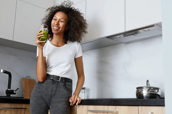 Woman drinking green detox juice, smoothie drink in kitchen — Stock Photo, Image