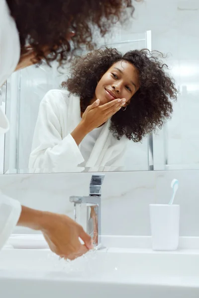 Skóra. Kobieta myje twarz wodą w umywalce w łazience — Zdjęcie stockowe