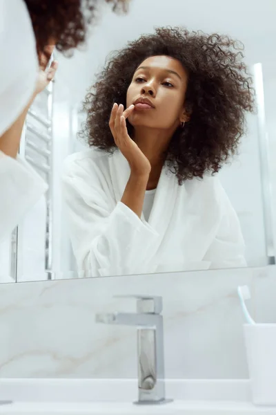 Уход за кожей губ. Женщина наносит бальзам для губ на портрет в ванной — стоковое фото