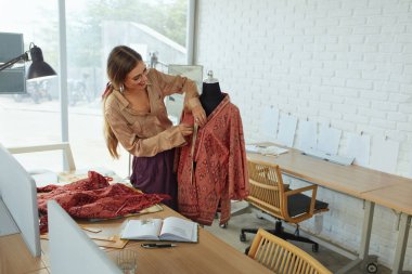 İş. Moda Tasarımcısı Atölyede. Güzel bayan terzi, mankenler üzerindeki elbiseyi ölçüyor ve çizim defterine bir şeyler yazıyor. Başarı Serbest Çalışan Kadın Çalışıyor.