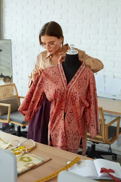 Projektant mody na warsztatach. Szczęśliwa kobieta w stylowych ciuchach pracująca w Atelier. Sukces Samozatrudniony Krawiec trzymając rękę na manekin. — Zdjęcie stockowe