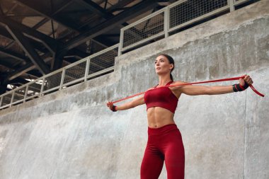 Fitness kızı. Dışarıdaki direniş bandıyla antrenman. Taş Duvara Karşı Egzersiz Yapan Formda Güçlü Kaslı Vücutlu Formda Kadın. Kentliler için Aktif Yaşam Tarzı.
