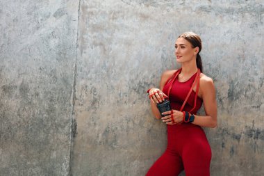 Fitness Kız Dinleniyor. Bir şişe Protein Kokteyli ile Moda Sporu Giyen Kadın Yoğun Çalışmadan Sonra Kırıldı. Şehir dışı Güçlü Kaslı Vücut ve Sağlıklı Yaşam İçin Egzersiz Yapıyor.