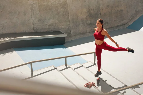 Entrenamiento en las escaleras. Chica en traje de fitness calentamiento antes de ejercicio intensivo. Moda Deportiva Mujer Entrenamiento al aire libre en el estadio. Entrenamiento para un cuerpo muscular fuerte como estilo de vida urbano . — Foto de Stock