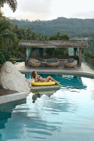 Mulher no flutuador de abacaxi na piscina nas férias de verão — Fotografia de Stock