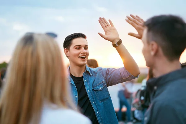 Молодой человек встречается с друзьями на открытом воздухе — стоковое фото