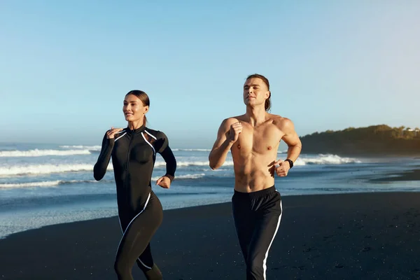 Beach. Man And Woman Running During Outdoor Workout. Sport Couple In Fashion Sportswear Training In Morning. Jogging Exercising Near Ocean On Summer Vacation As Part Of Active Lifestyle.