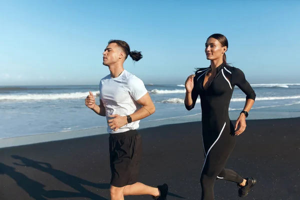 Un paio di Running On Beach. Bello uomo e sexy donna in moda sportivo abito jogging lungo oceano costa di mattina. Stile di vita attivo e sport ricreativo durante le vacanze estive. — Foto Stock