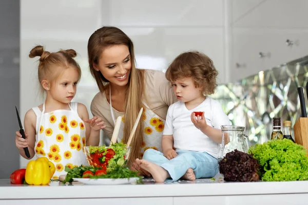 厨房里有孩子的妇女烹调健康食品 — 图库照片