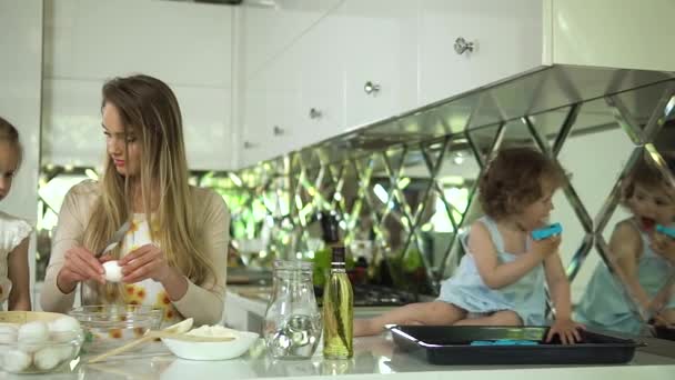 Mãe com filhas cozinhar alimentos na cozinha moderna luz — Vídeo de Stock