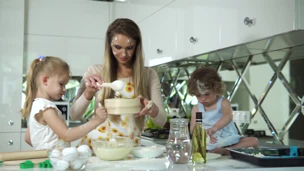 Familienküche. Mutter mit Töchtern bereitet Teig zum Backen vor — Stockvideo