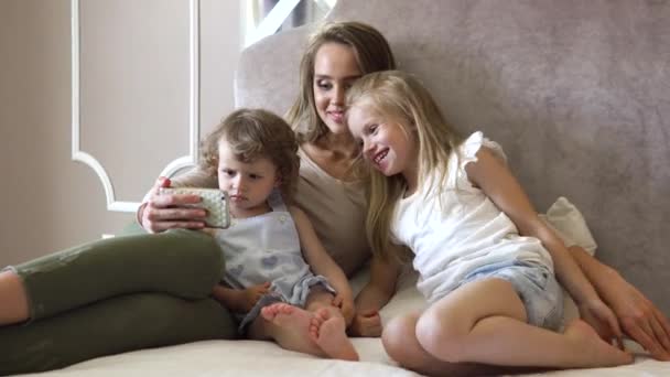 Семья с телефоном. Женщина и дети с помощью телефона в спальне — стоковое видео