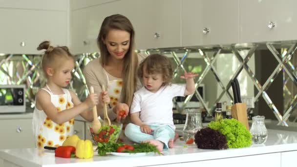 Frau mit Kindern kocht Gemüsesalat in der Küche — Stockvideo