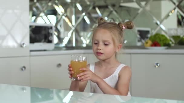 Kinderernährung. Kleines Mädchen trinkt Saft in der Küche — Stockvideo