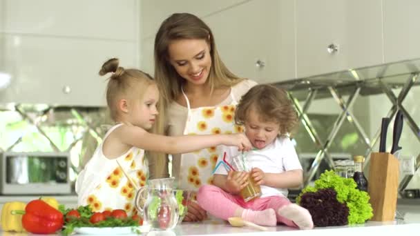 Mulher com crianças preparando salada de legumes na cozinha moderna — Vídeo de Stock