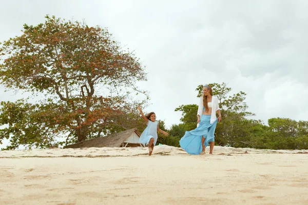 Kid And Woman On Beach. Happy Mother And Daughter Enjoying Summer Vacation At Tropical Ocean. Mom In Fashion Maxi Dress Having Fun With Child. Weekend With Children As Lifestyle. — Stock Photo, Image