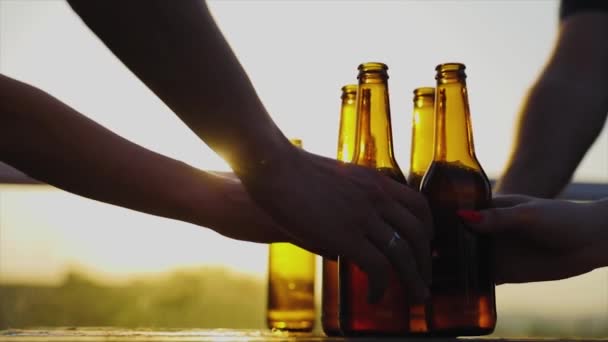 Amigos bebiendo cerveza al aire libre. Botellas en las manos Primer plano — Vídeos de Stock