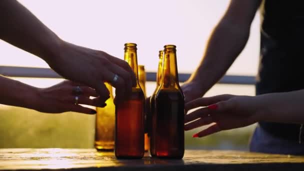 Друзья пьют пиво на открытом воздухе. Бутылки в руках крупным планом — стоковое видео