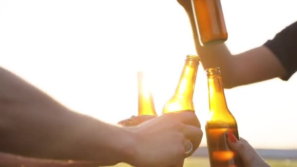 Amigos bebiendo cerveza al aire libre. Botellas en las manos Primer plano — Vídeo de stock