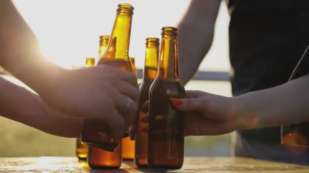 Amigos bebiendo cerveza al aire libre. Botellas en las manos Primer plano — Vídeo de stock