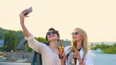 Dışarıda telefonda fotoğraf çeken, bira içen mutlu kadınlar.