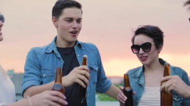 Mutlu arkadaşlar bira içiyor, şişelerle tezahürat yapıyor ve dans ediyor.