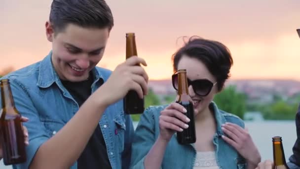 Amigos felizes bebendo cerveja, torcendo com garrafas e dançando — Vídeo de Stock
