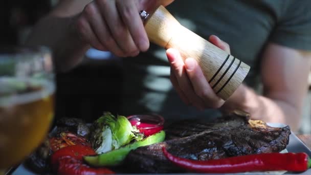 Еда крупным планом. Man Hand Seasoning Steak Meat with Grounded Pepper — стоковое видео