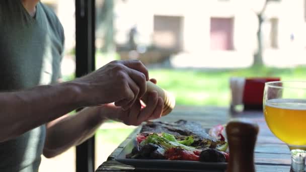 Primer plano hombre comiendo comida en restaurante condimento carne con pimienta — Vídeos de Stock