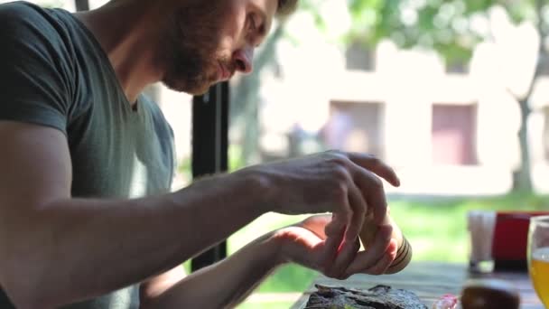 Mann isst Essen im Restaurant, würzt Fleischsteak mit Pfeffer — Stockvideo