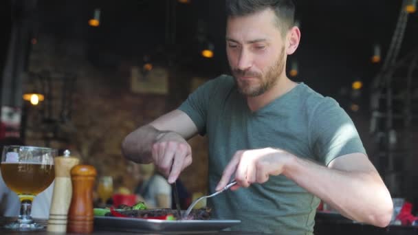 Hombre comiendo comida en el restaurante, cortando filete de carne con cuchillo — Vídeo de stock