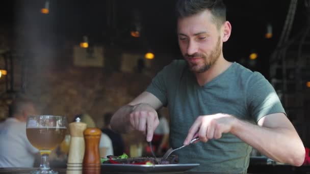 Uomo che mangia cibo al ristorante, tagliando carne bistecca con coltello — Video Stock